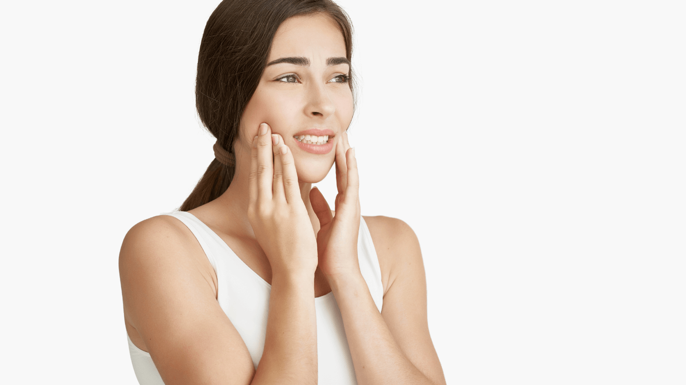 Woman holding her jaw with both hands, wincing in tooth pain